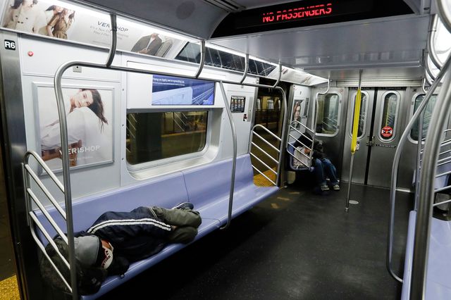 Two men stretch out on a subway car in early May, shortly after the subway system was shut down overnight.